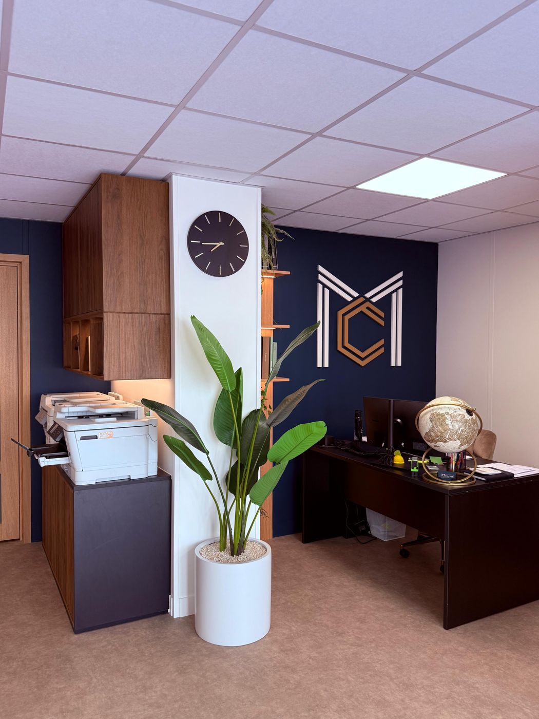 Logo MC sur le mur, imprimante et rangements